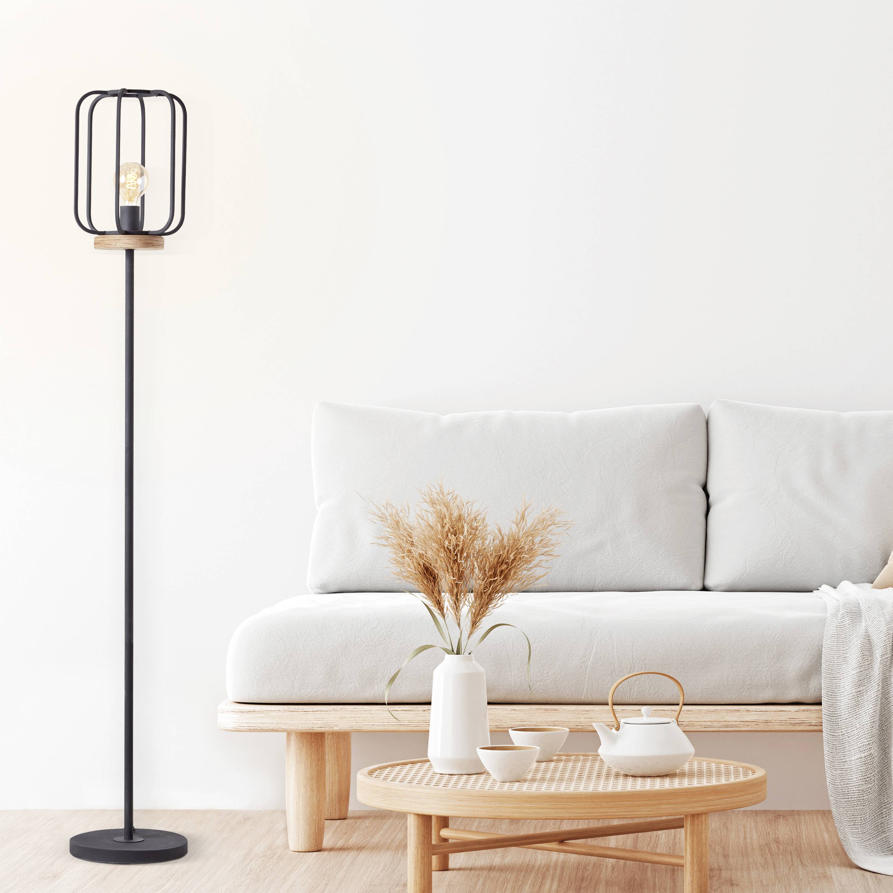 Ein modernes Wohnzimmer mit einem weißen Sofa, einer Stehlampe und einem Couchtisch mit Dekoration. Helle, minimalistische Einrichtung.