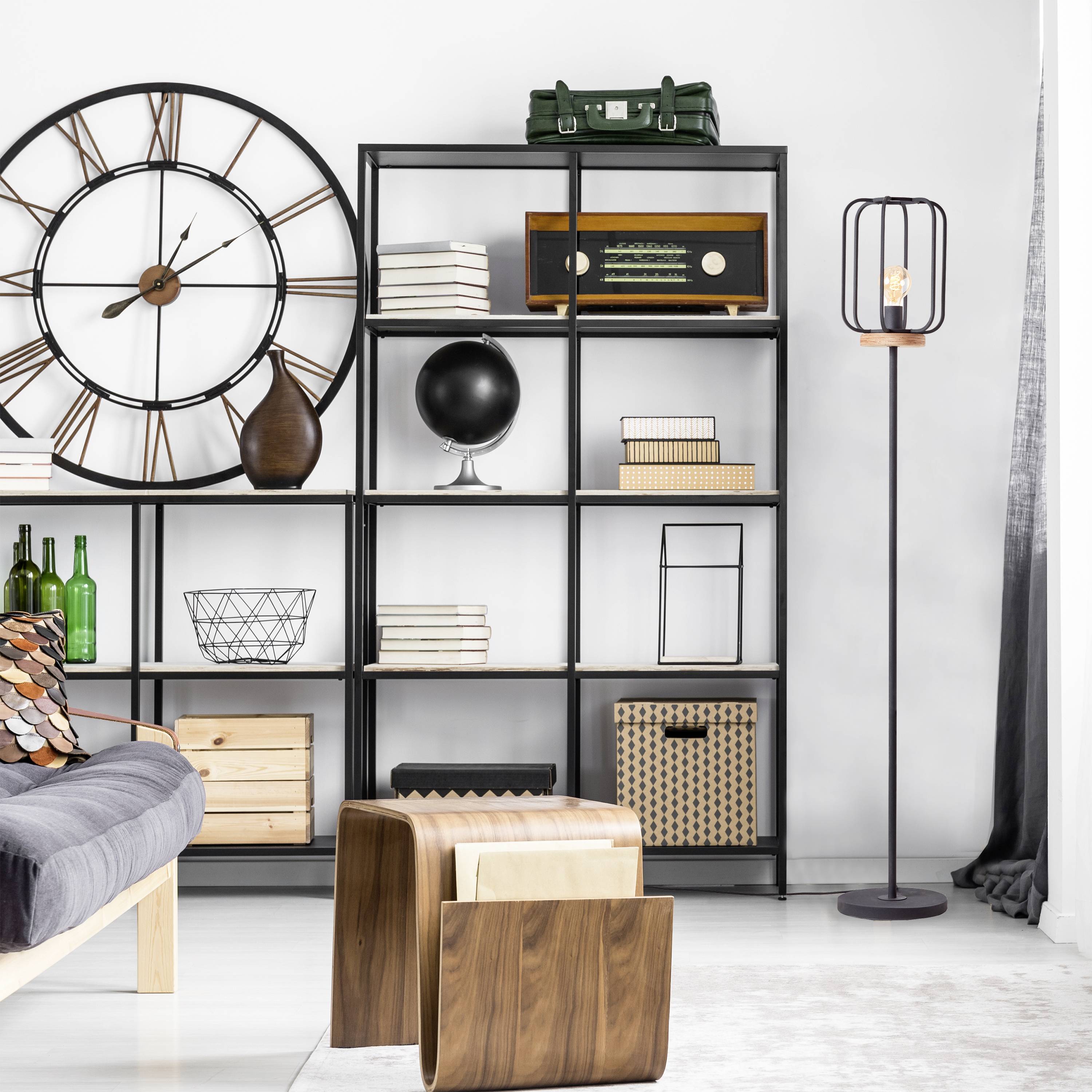 Wohnzimmer mit grauem Sofa, großen Wanduhr, schwarzen Regalen mit Büchern und Dekorationen, und Holzbeistelltischen. Elegantes, modernes Design.