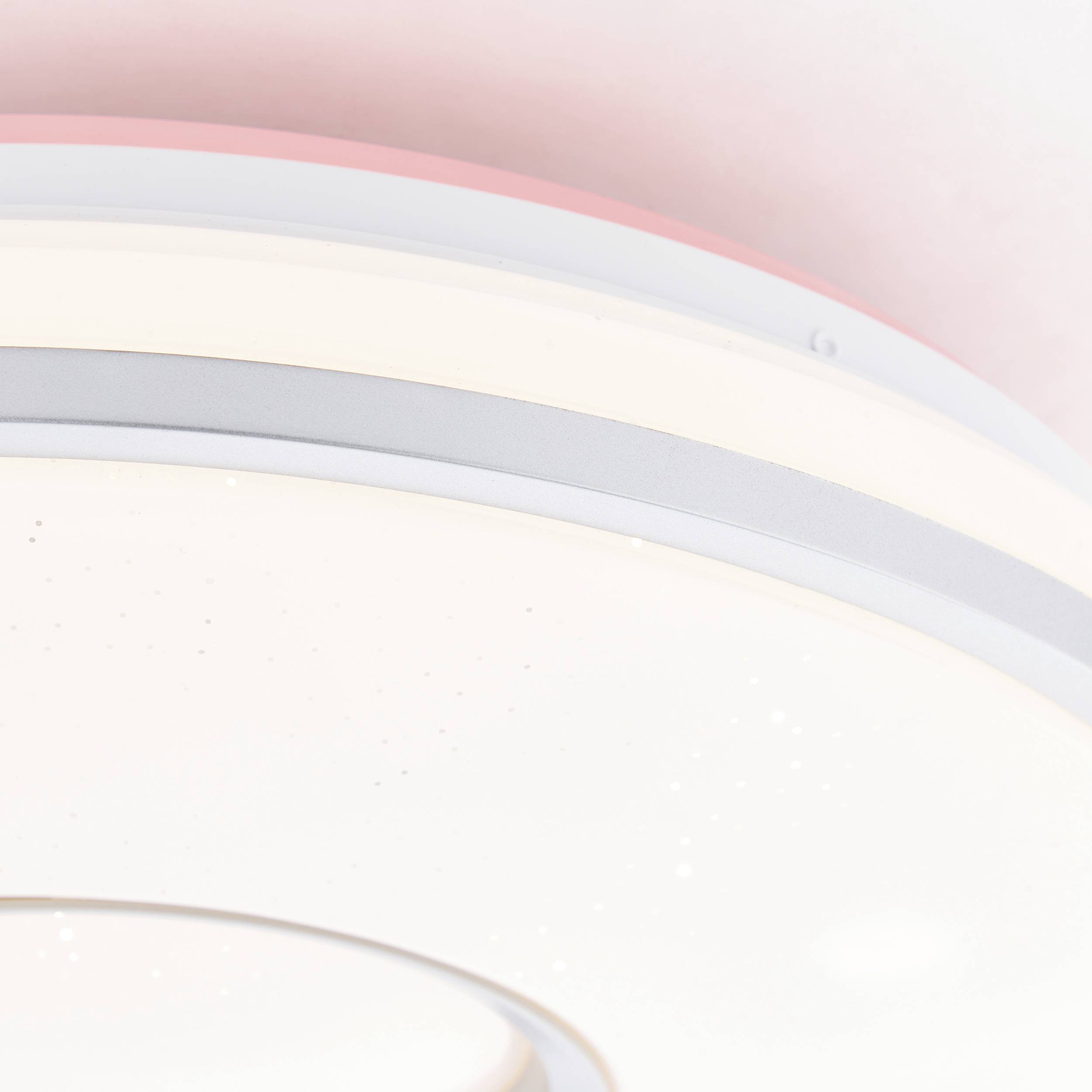 Ein moderner, runder Deckenventilator mit integrierter Beleuchtung und glatter, weißer Oberfläche, vor pastellfarbenem Hintergrund.