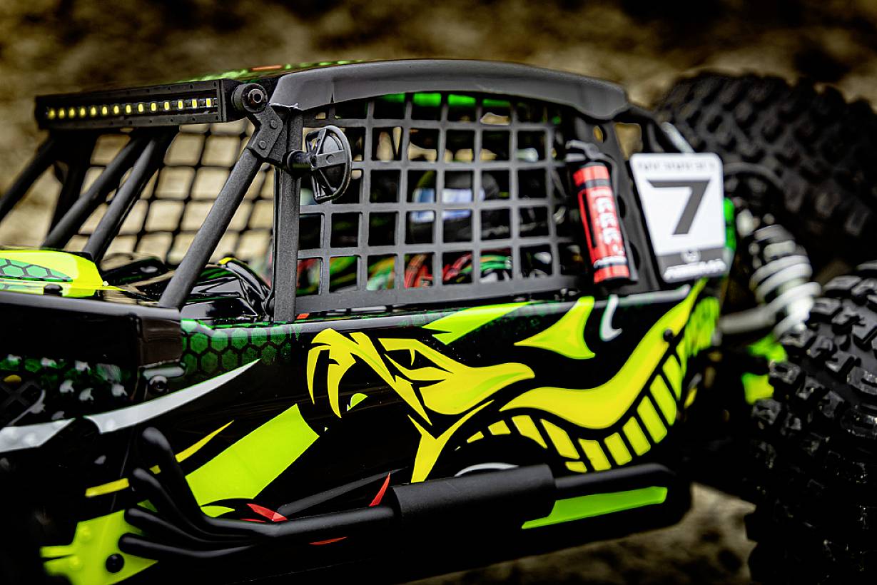 Nahaufnahme eines ferngesteuerten Geländewagens. Das Fahrzeug ist sportlich in leuchtendem Gelb und Grün gestaltet und hat große Reifen.