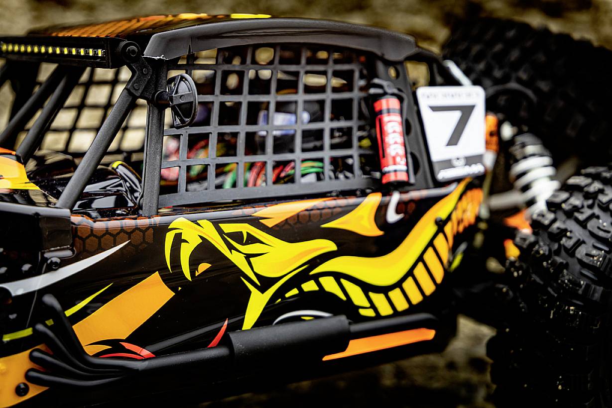 Ein leuchtend bemalter Geländewagen mit Nummer '7', Gitterfenster und grobstolligen Reifen, gestaltet für Offroad-Rennen.