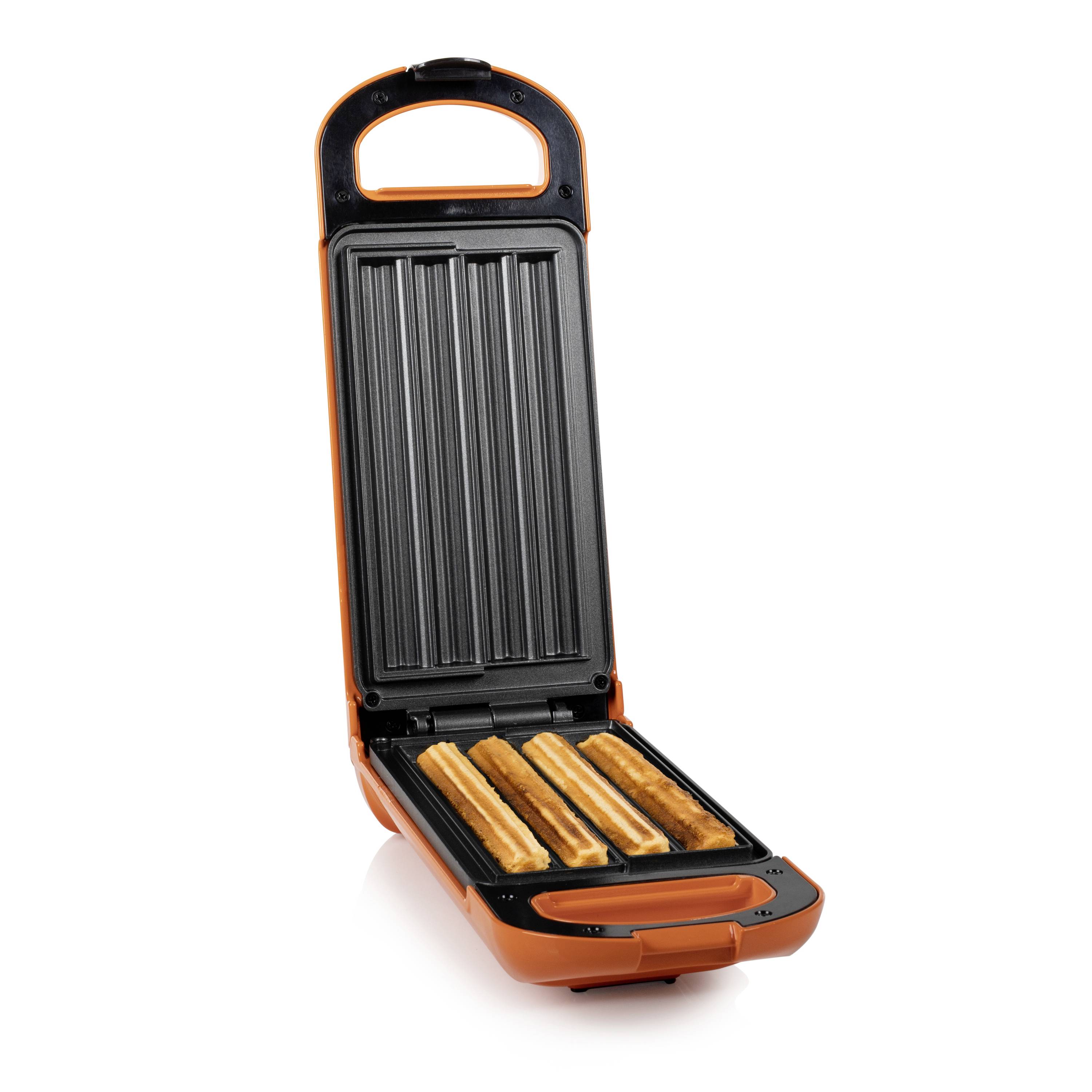 Ein orangefarbenes Waffeleisen backt drei lange Churros auf einer gerippten Grillplatte.