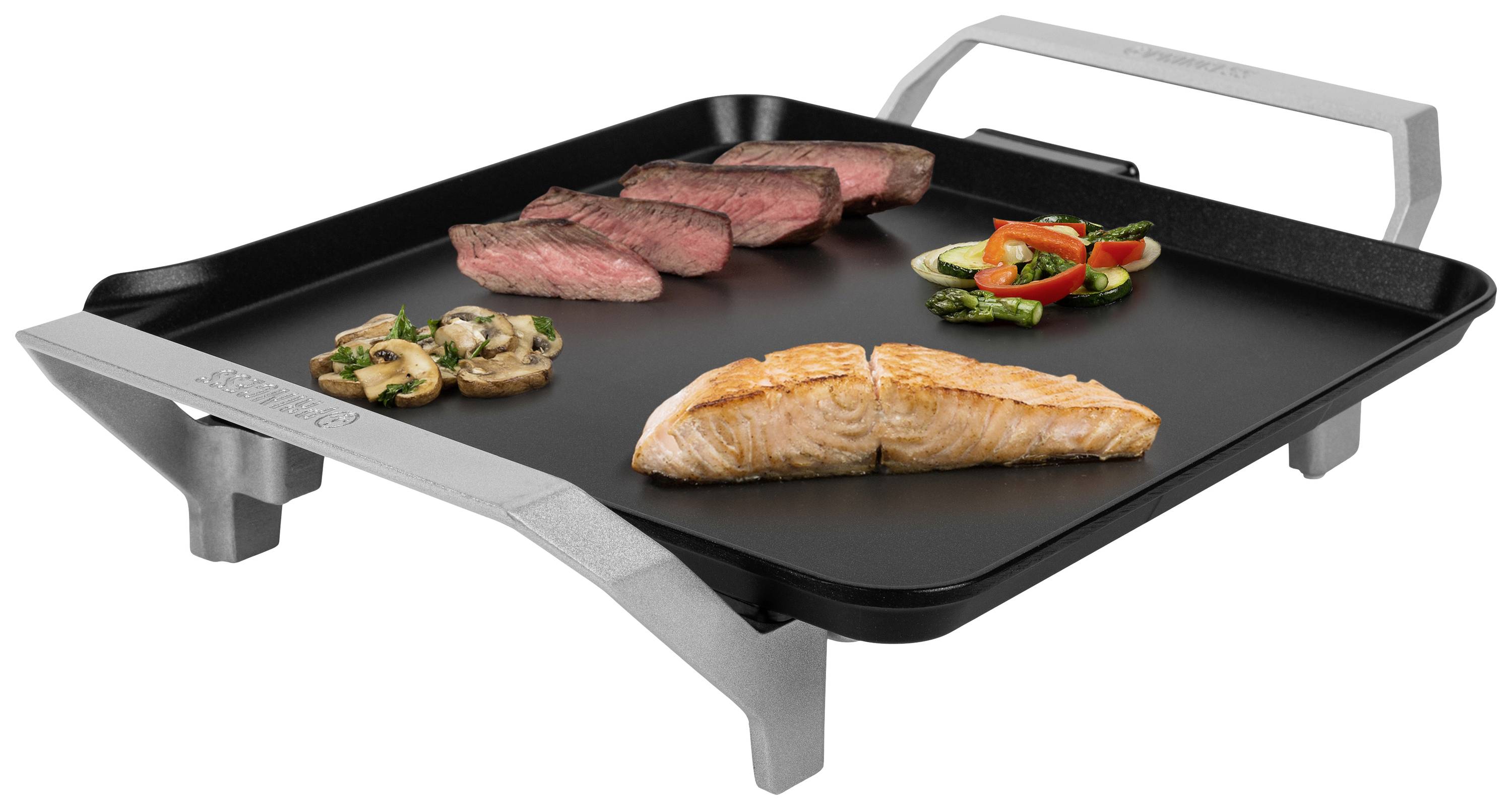 Grillplatte mit gegrilltem Lachs, Steak, Champignons und Gemüse, quadratisch und erhitzt, mit Griffen an den Seiten.