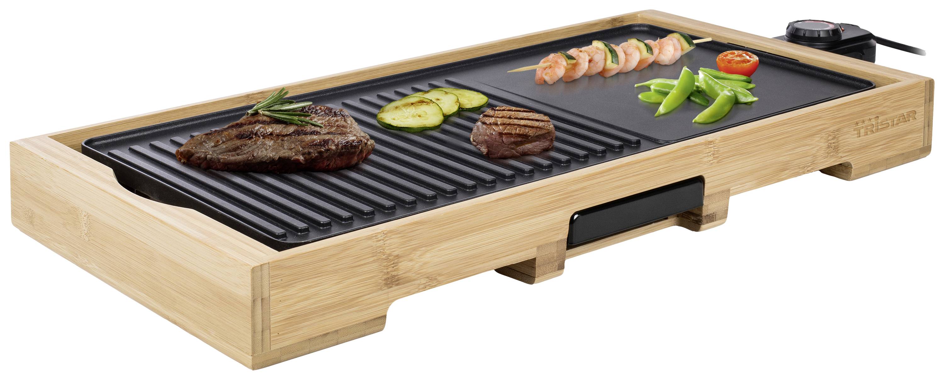 Elektrischer Tischgrill mit Bambusrahmen. Auf der Grillplatte liegen Steak, Zucchini, Garnelenspieß, Tomate und Bohnen.