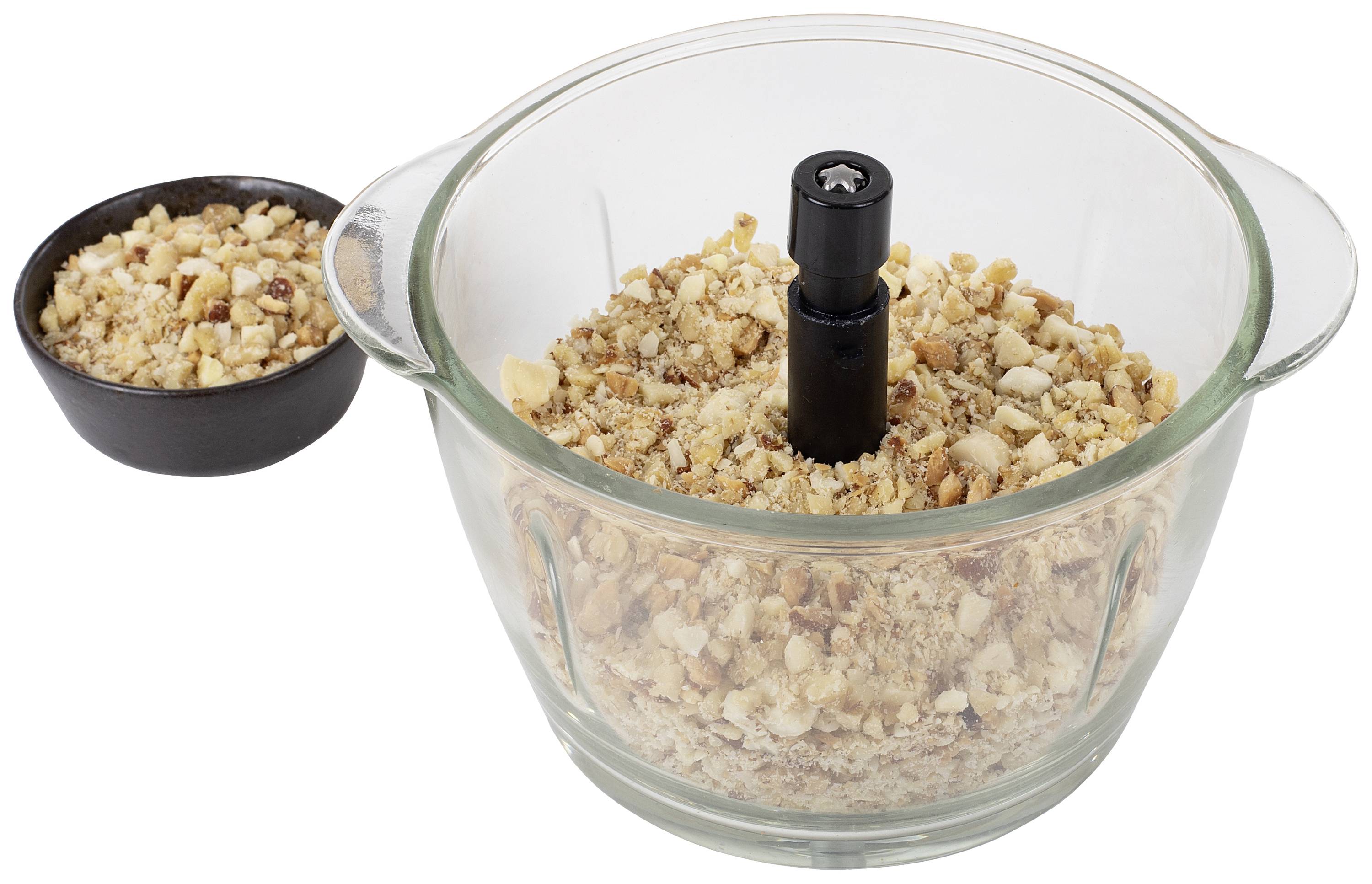Zerkleinerte Nüsse in einer Glasschale mit schwarzem Kunststoffgriff in der Mitte, daneben liegt eine kleine Schale mit weiteren Nüssen.
