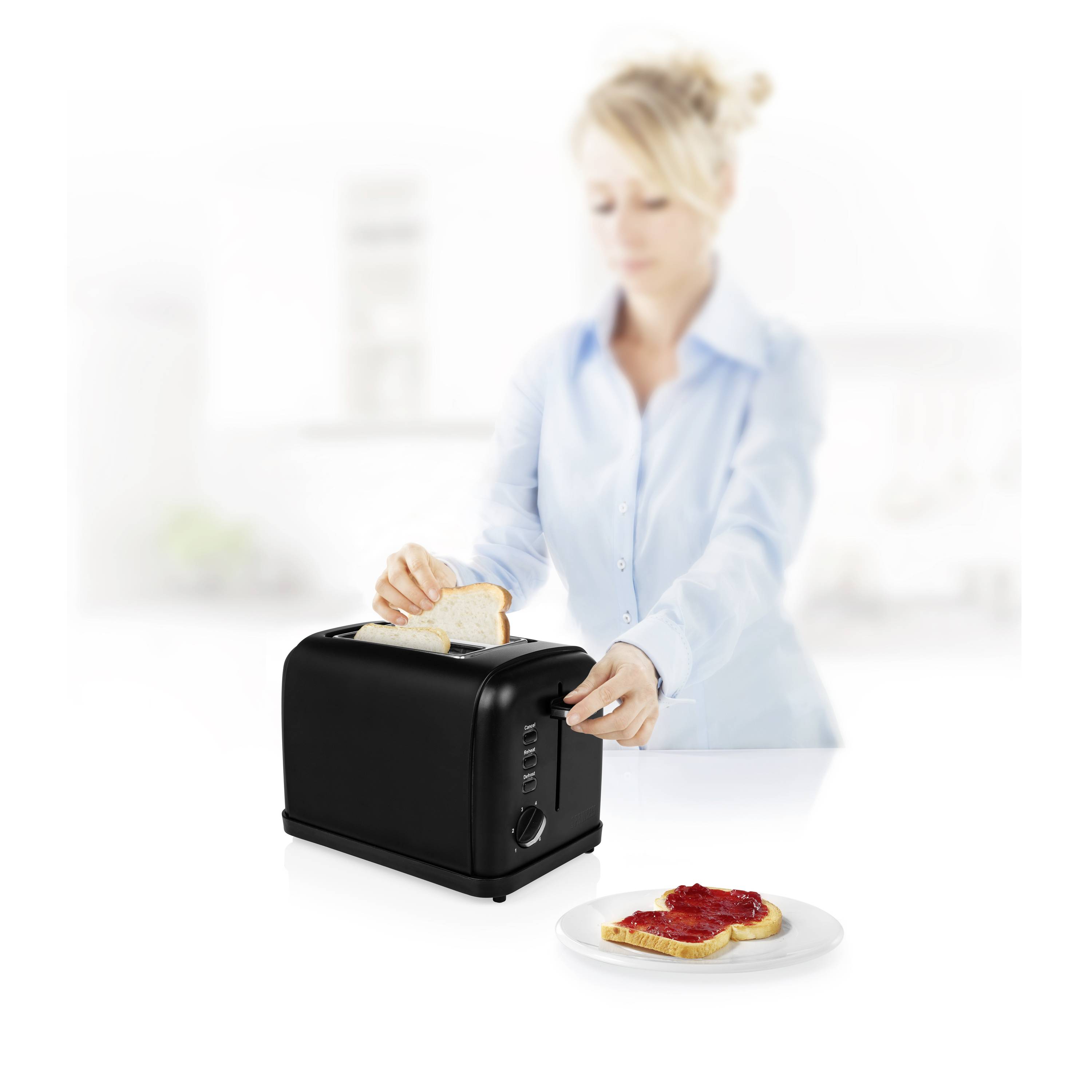 Eine Person röstet Toast in einem schwarzen Toaster. Ein fertiger Toast mit Marmelade liegt auf einem weißen Teller im Vordergrund.