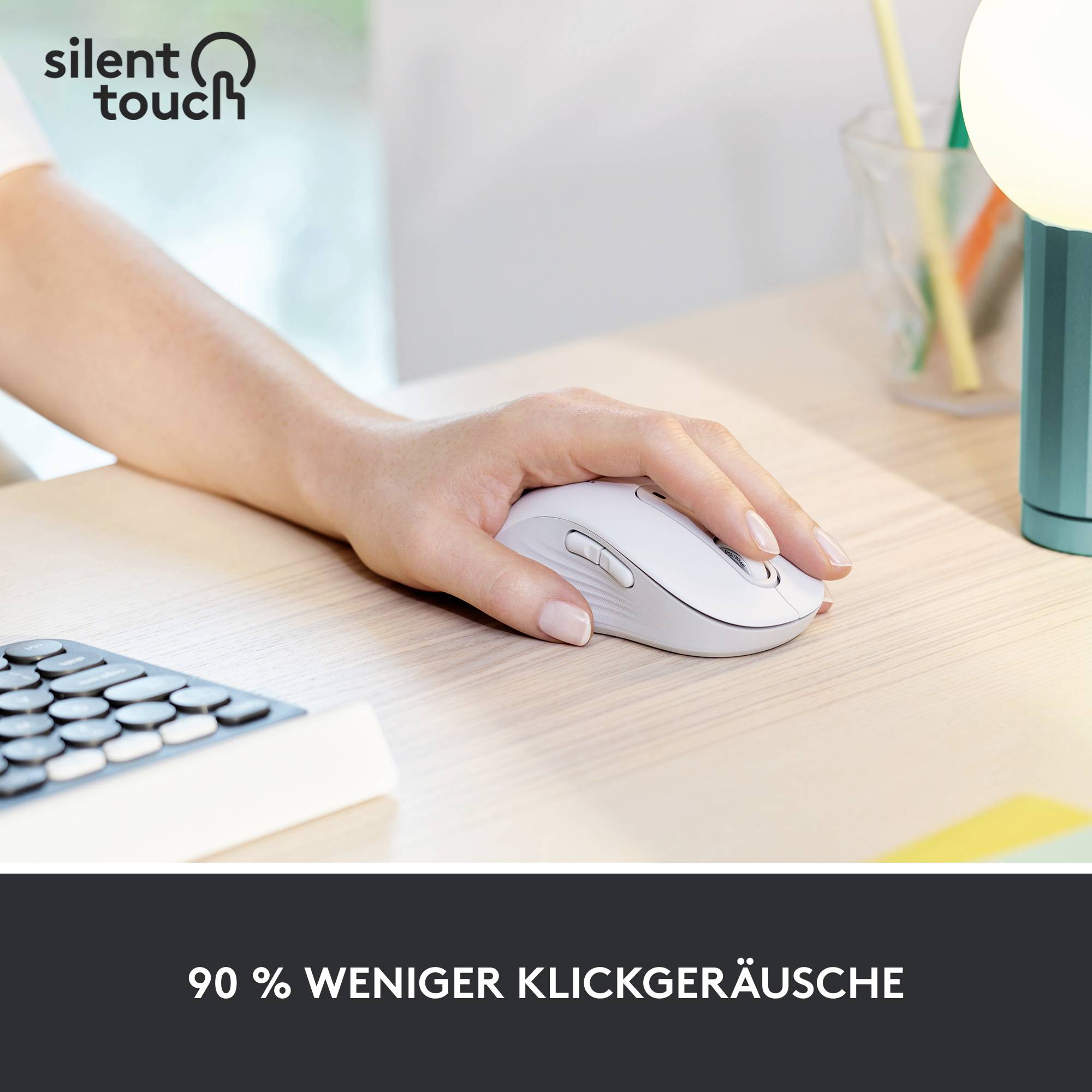 Eine Hand benutzt eine weiße Computermaus auf einem Schreibtisch. Text im Bild: '90 % weniger Klickgeräusche'.