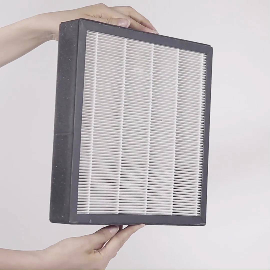 Person hält einen rechteckigen, weißen Luftfilter mit schwarzem Rahmen. Der Filter wird horizontal vor einem neutralen Hintergrund präsentiert.