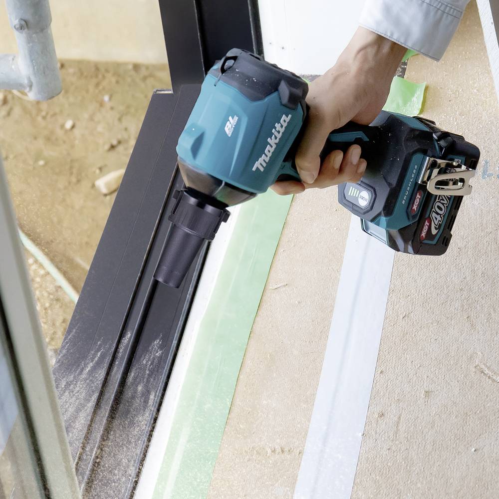 Eine Hand hält einen blauen Akku-Schlagschrauber, der auf einen Metallrahmen zielt. Dieser wird an einer Baustelle verwendet.