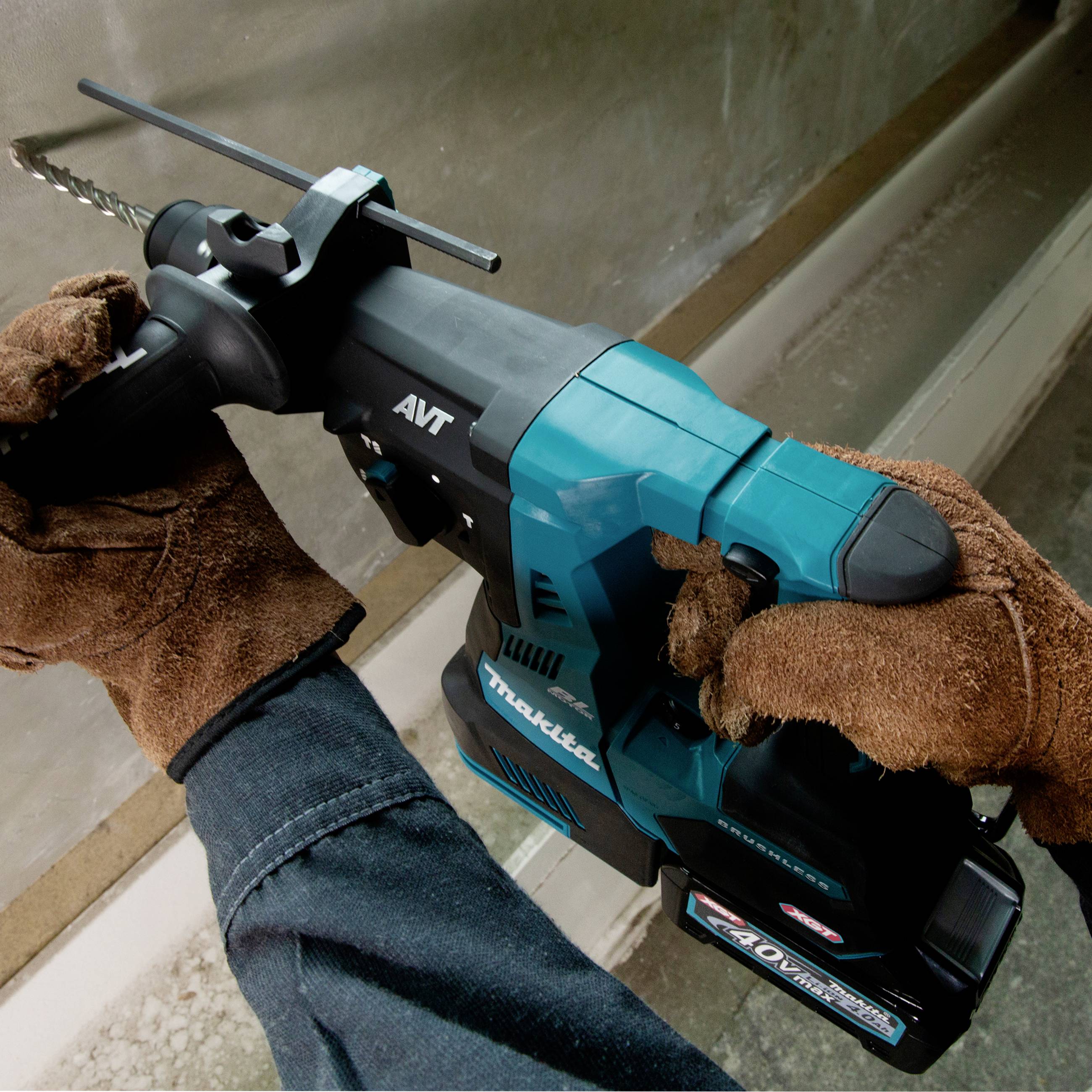 Eine Person hält eine blaue Bohrmaschine mit einem schwarzen Griff. Die Maschine hat eine Metallbohrspitze. Hände sind mit braunen Handschuhen bedeckt.