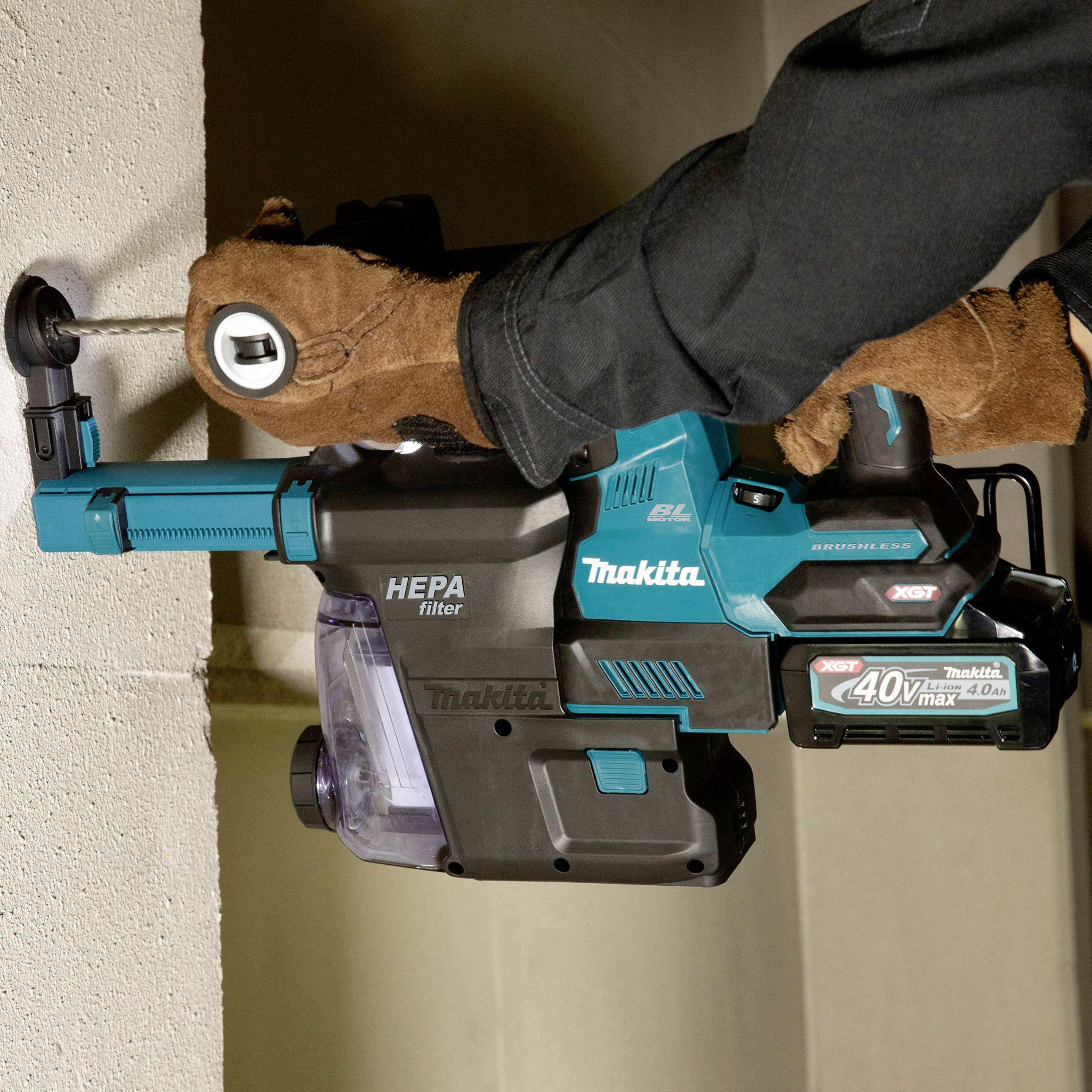 Eine Person benutzt einen Makita-Bohrhammer, um Löcher in eine Betonwand zu bohren. Der Bohrer hat einen HEPA-Filteraufsatz.