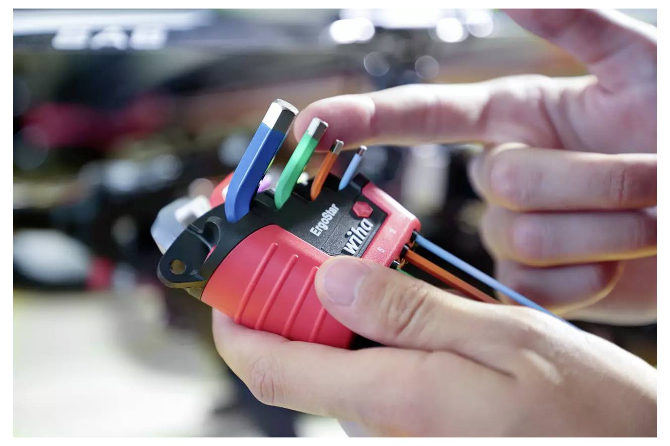 Hände halten ein Gerät mit farbigen Drähten, das eine Verdrahtungs- oder Elektroinstallation darstellt.