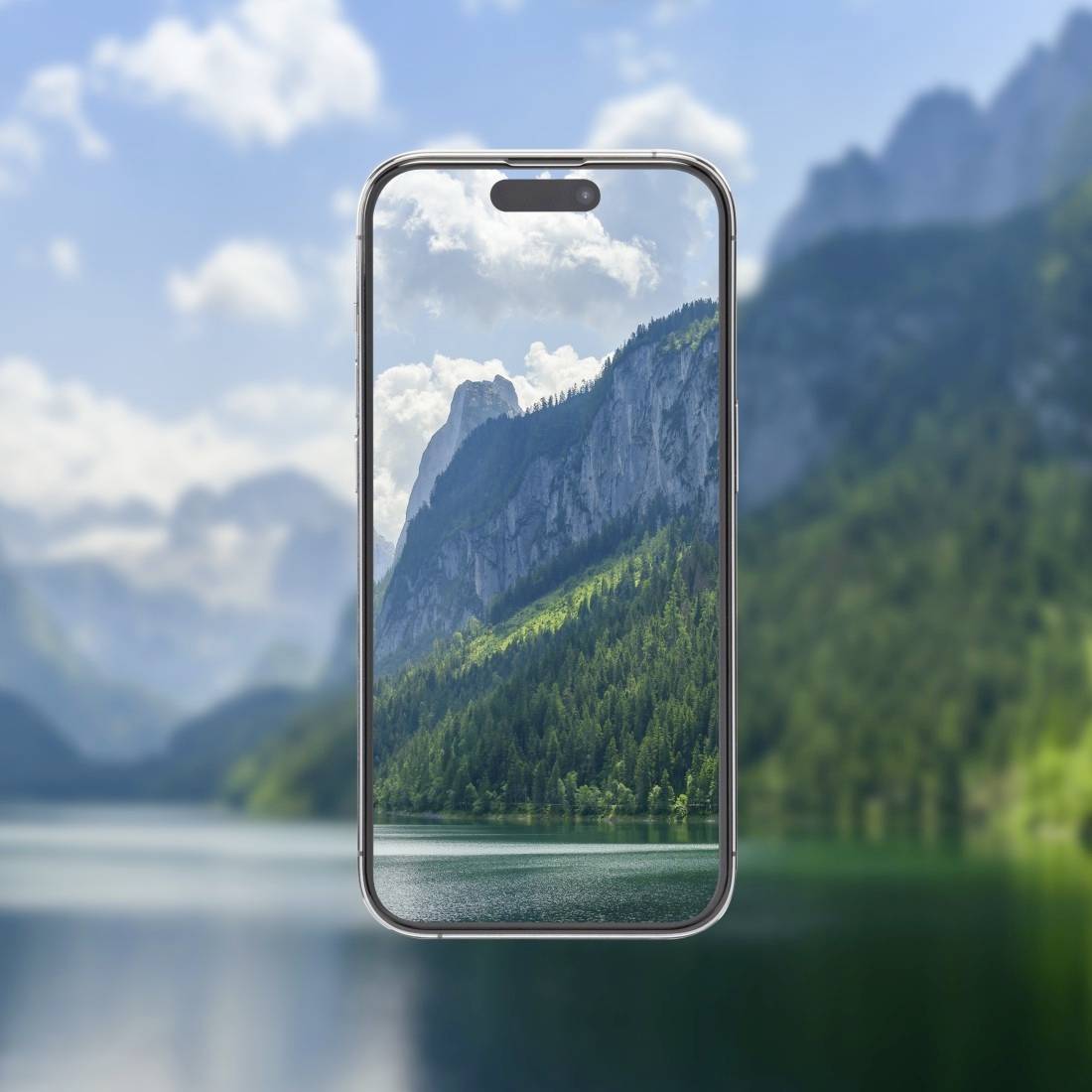 Ein Smartphone zeigt ein Bergpanorama: grüne Wälder, steile Felsen und blauer Himmel. Im Hintergrund ein See mit bewaldetem Ufer.