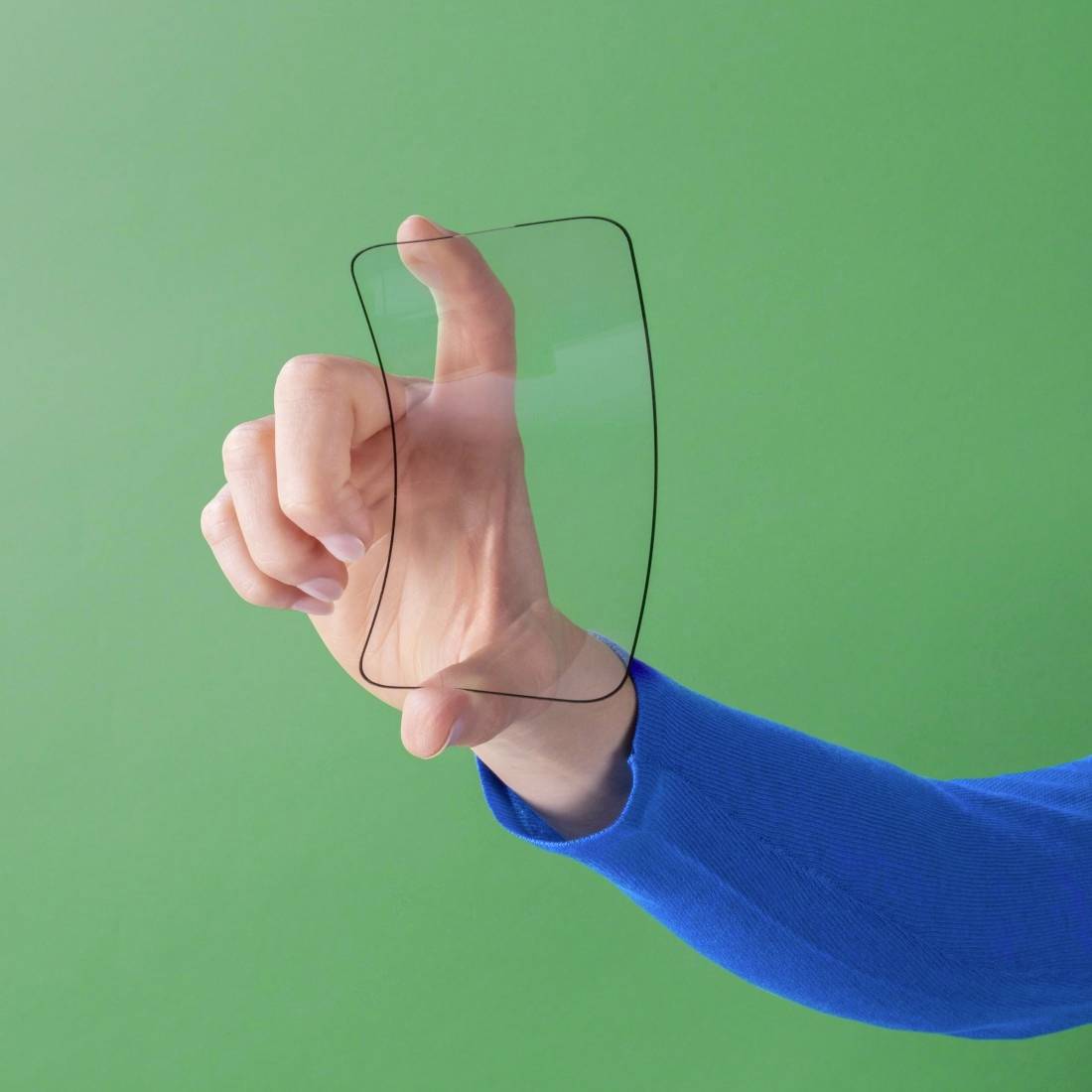 Eine Hand, die ein durchsichtiges, unsichtbares Rechteck gegen einen grünen Hintergrund hält, symbolisiert moderne Technik.