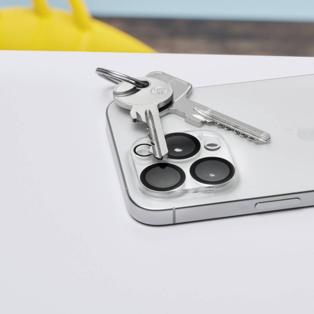 Ein Smartphone liegt auf einem Tisch mit einem Schlüsselbund darauf. Das Gerät zeigt die Rückseite mit einer mehrfachen Kameralinse.