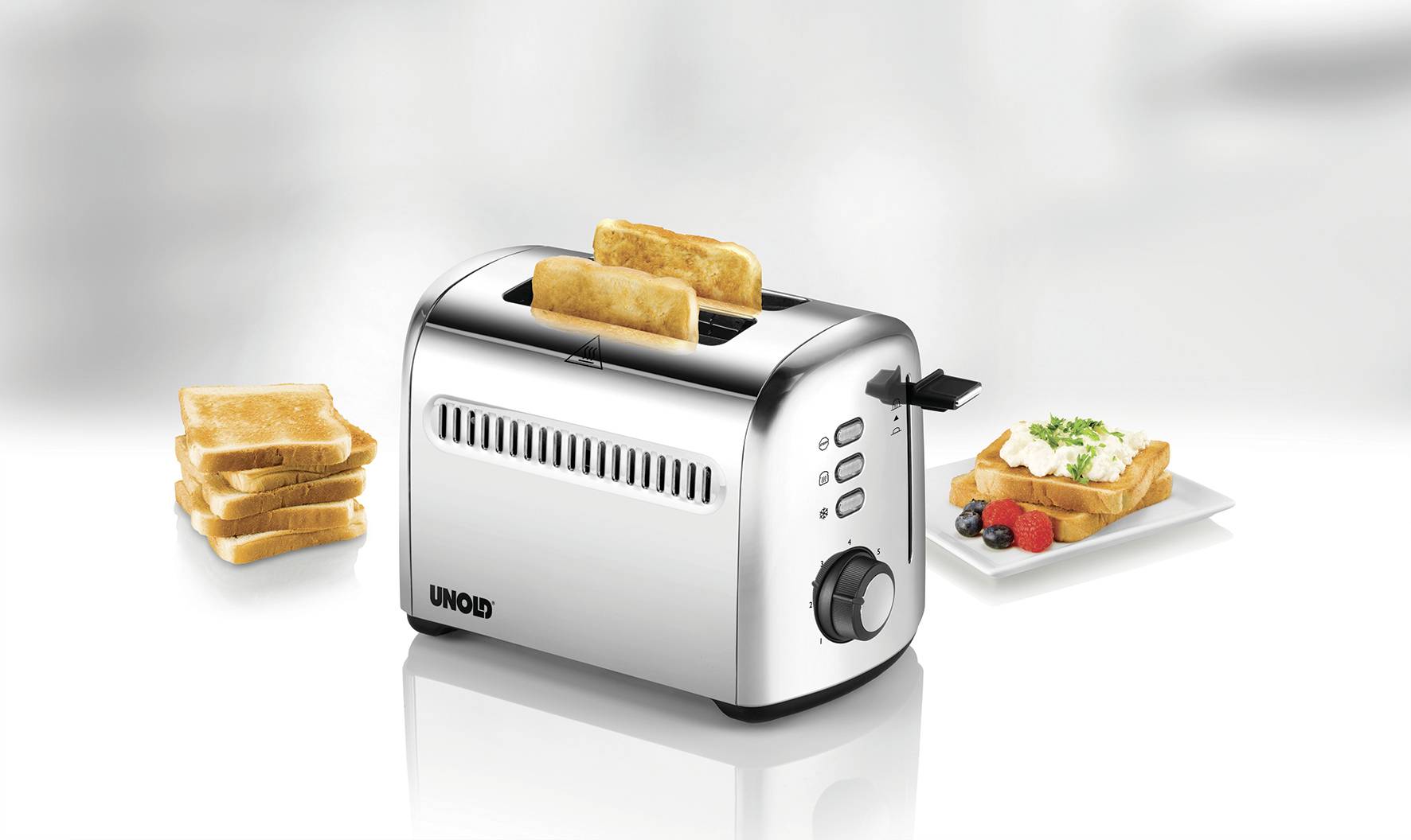 Ein Toaster mit zwei Toastscheiben, links ein Stapel ungetoastetes Brot, rechts ein Teller mit gebuttertem Toast und Beeren.