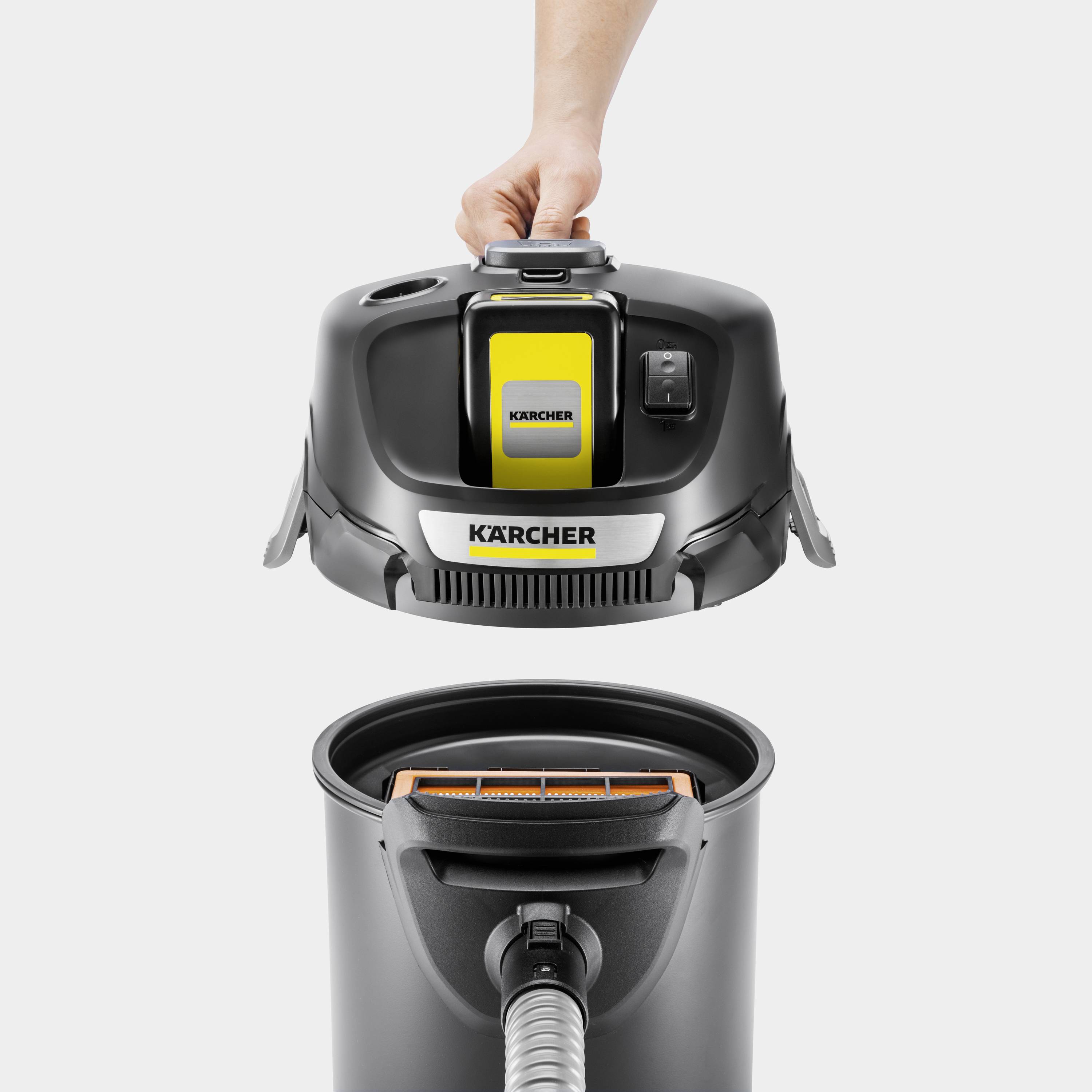 Eine Person hebt den oberen Teil eines KÄRCHER Industriesaugers ab, um den Innenraum zu zeigen.
