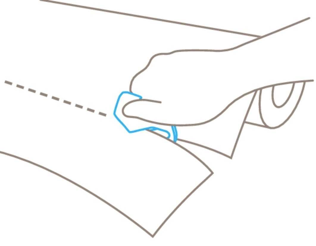 Jemand schneidet Papier entlang einer gestrichelten Linie mit einem blauen Schneidewerkzeug.