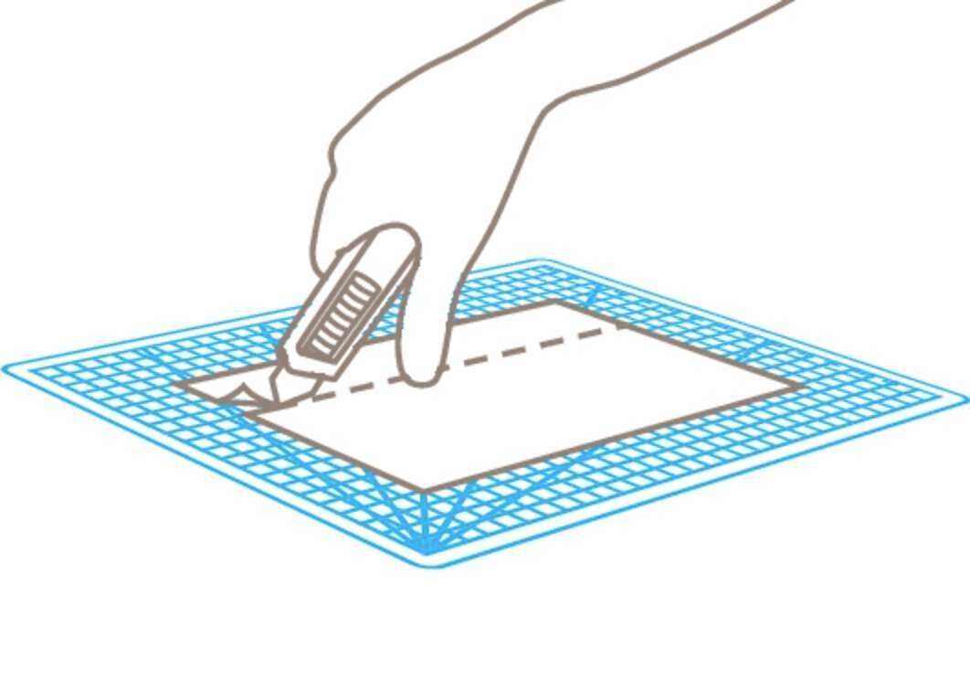 Eine Hand schneidet entlang einer gestrichelten Linie auf Papier, das auf einer Schneidematte liegt, mit einem Cutter.
