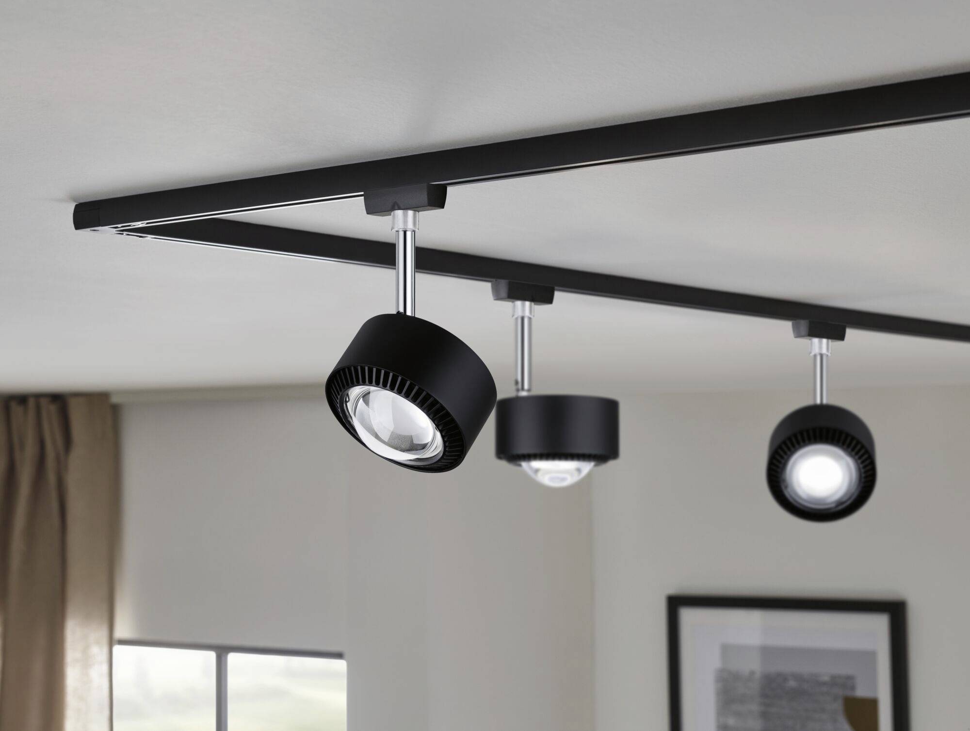 Eine moderne schwarze Deckenleuchte mit drei verstellbaren Spots, montiert an einer Schiene, beleuchtet einen Wohnraum.