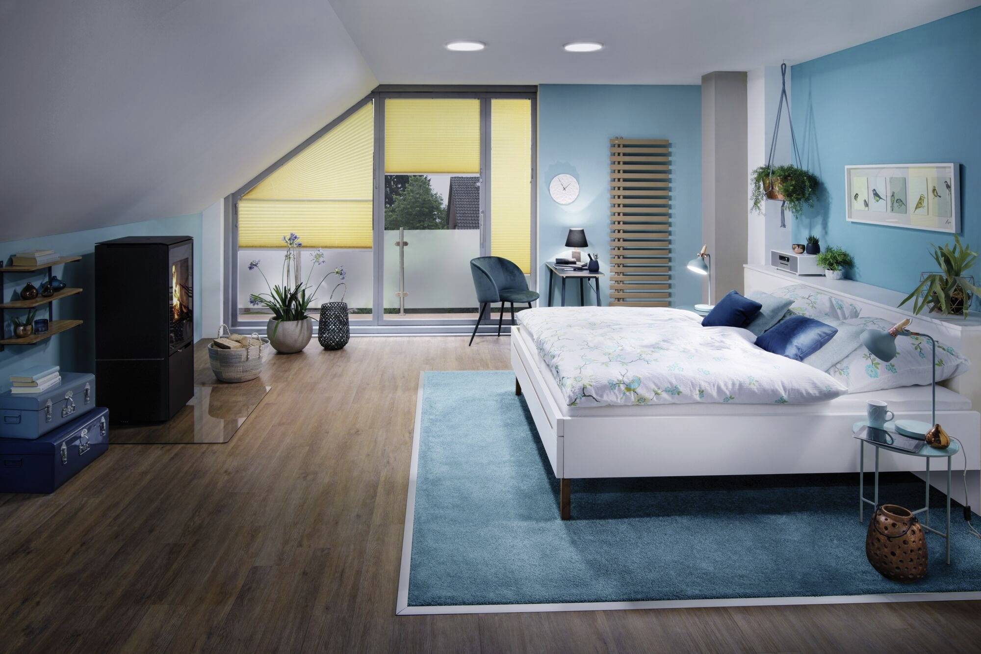 Schlafzimmer mit modernem Design: weißes Bett, blaue Akzente, Holzboden, Kamin. Große Fenster mit gelben Jalousien, Pflanzen als Dekoration.