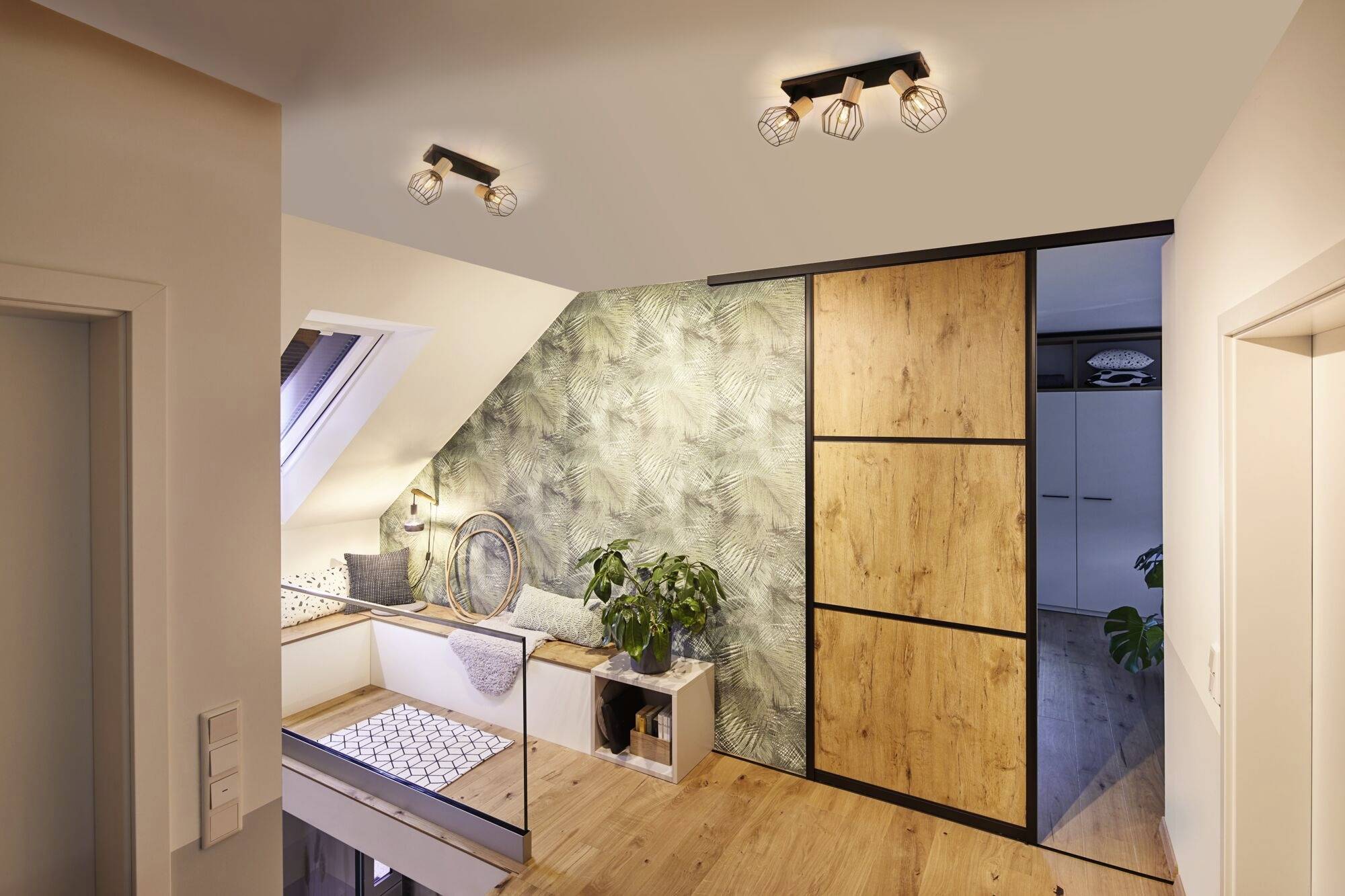 Ein modernes, gut beleuchtetes Dachgeschoss mit Holz- und Pflanzenakzenten. Eine Sitzecke am Fenster, daneben ein großer Schrank.