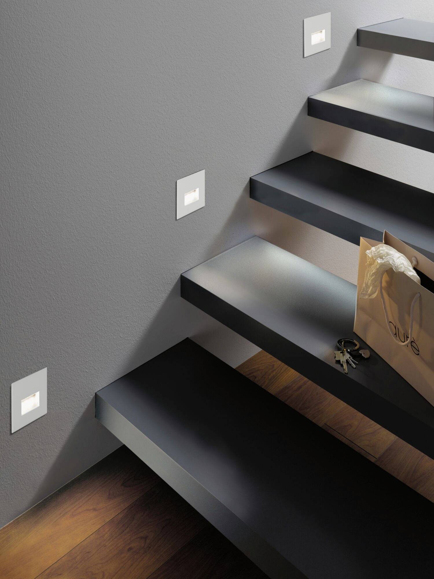 Eine modern gestaltete Treppe mit seitlich angebrachten Lichtern. Auf der Stufe liegt eine braune Einkaufstasche und ein Schlüsselbund.