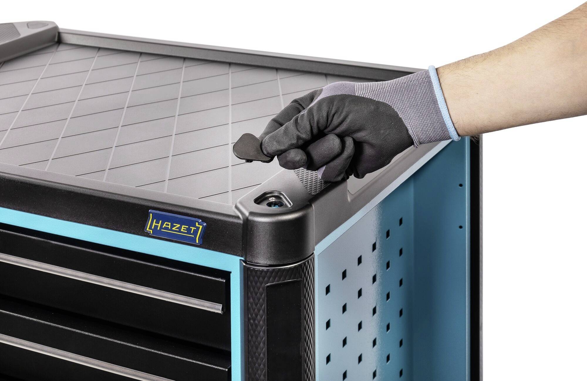 Eine Hand mit Handschuh betätigt das Schloss eines Werkzeugschranks der Marke 'Hazet'. Der Schrank ist metallisch-blau.