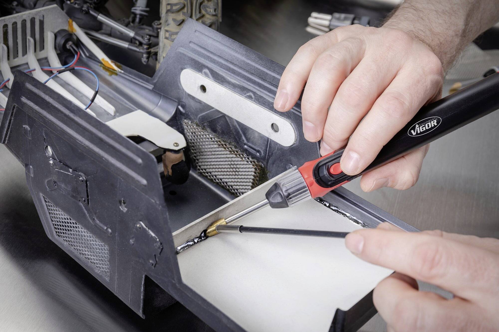 Person lötet mit einem Lötkolben an einer Metalleinrichtung, zeigt präzise Handarbeit im technischen Kontext.