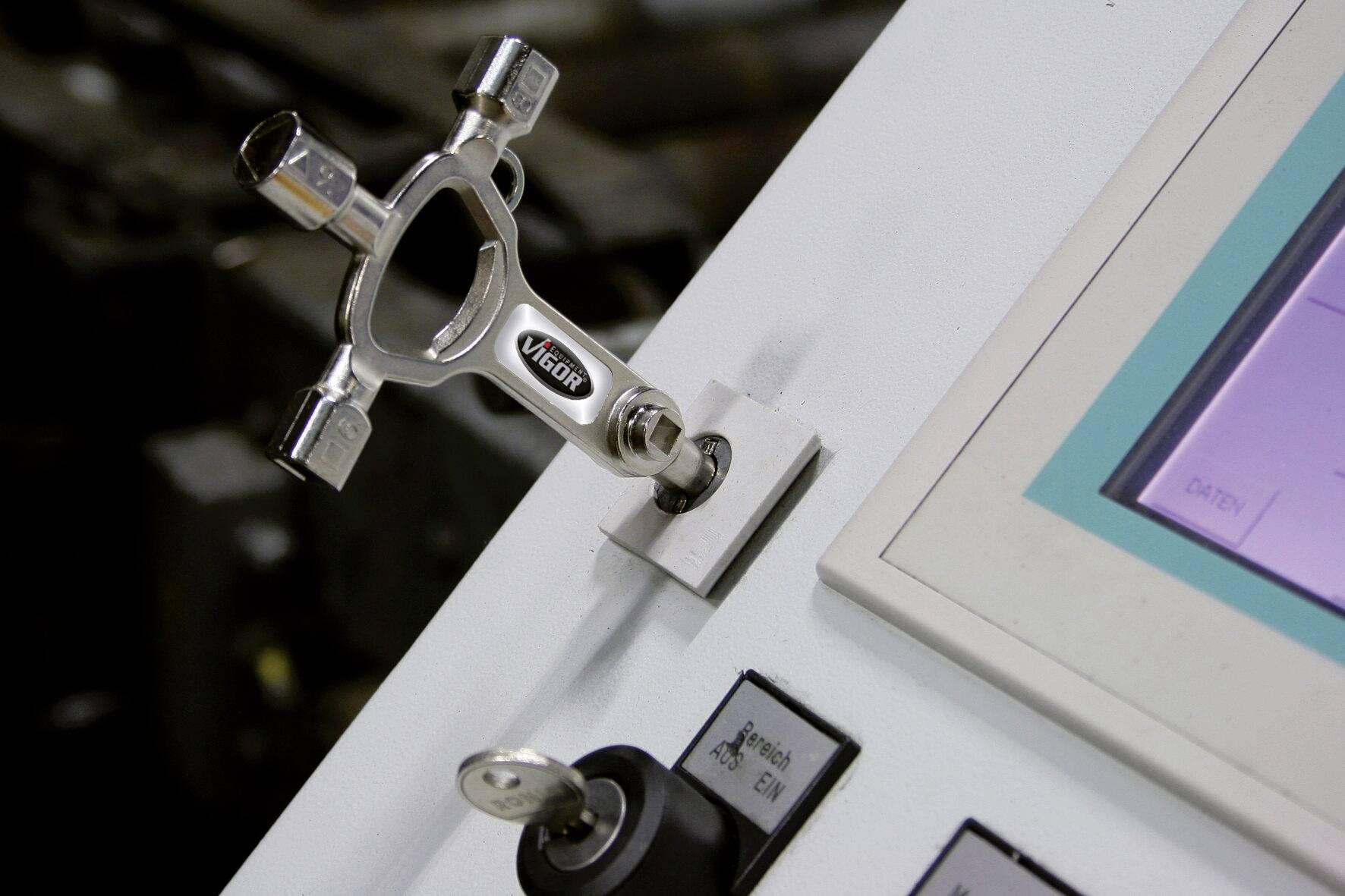 Ein Steuerbord mit einem Hauptschlüssel zeigt eine Verriegelungsvorrichtung in einem industriellen Umfeld. Auf der rechten Seite befindet sich ein Display.