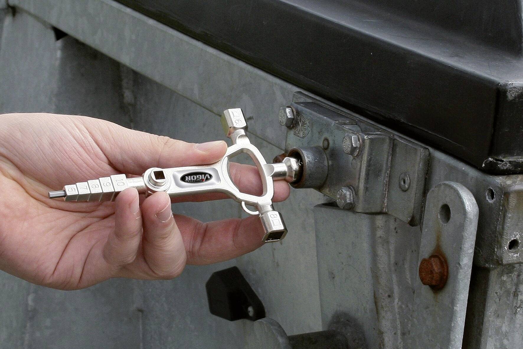 Eine Person verwendet einen Vierkantschlüssel, um ein Schloss an einer Metalltür zu öffnen.