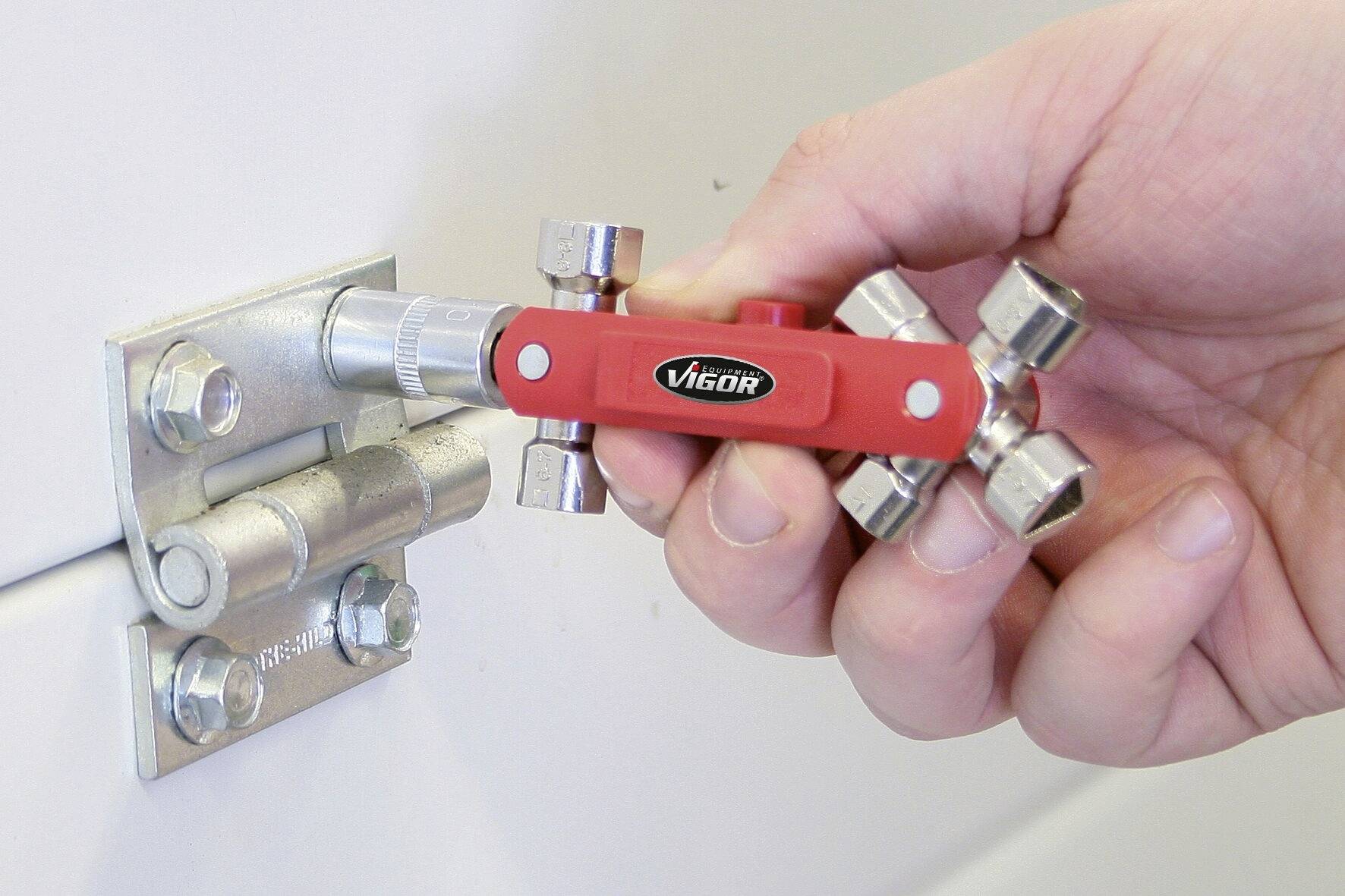 Eine Hand hält einen roten Drehmomentschlüssel, der an einem Metallscharnier befestigt ist.