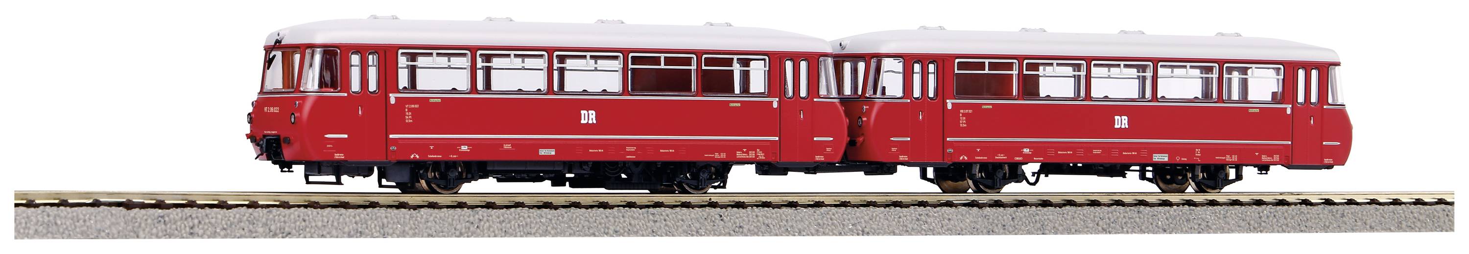 Ein roter Schienenbus mit zwei Wagen steht auf einem Gleis. Er hat ein klassisches Design und weiße Fensterränder.