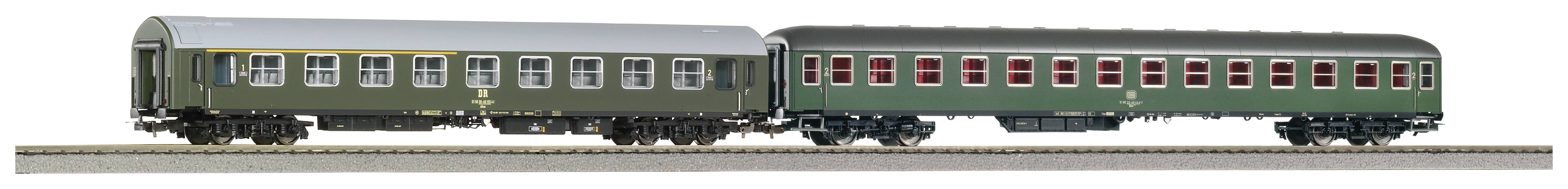 Zwei grüne Eisenbahnwaggons auf Gleisen, jeder mit rot umrandeten Fenstern und silbernem Dach.