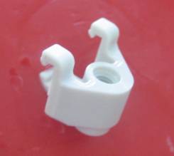 Ein weißes, plastikähnliches Befestigungselement mit zwei Haken auf einem roten Hintergrund.