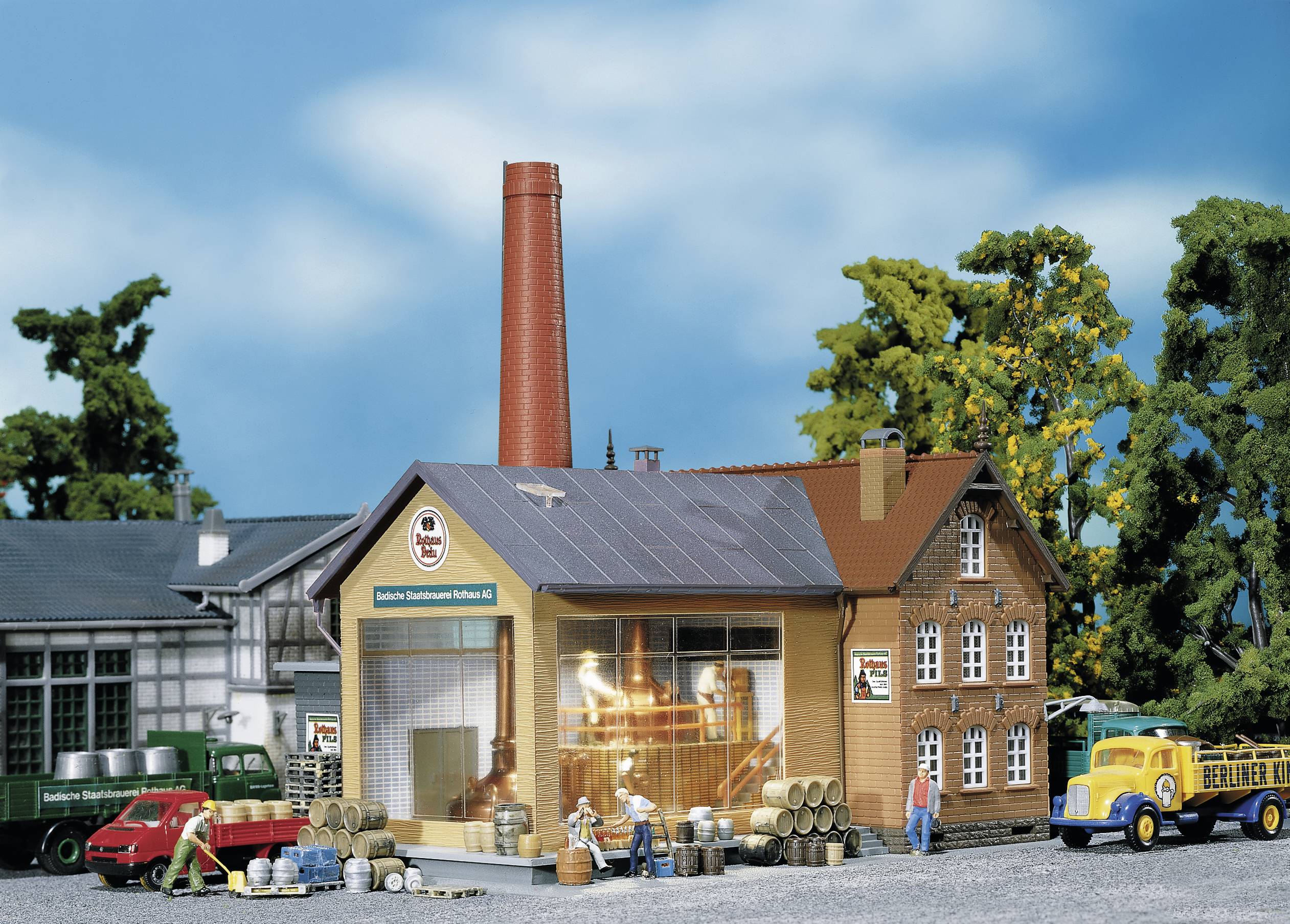 Miniatur-Szene einer Brauerei mit Gebäude, Lastwagen und Arbeitern beim Transport von Fässern. Modell zeigt ländliche Brauereiumgebung.
