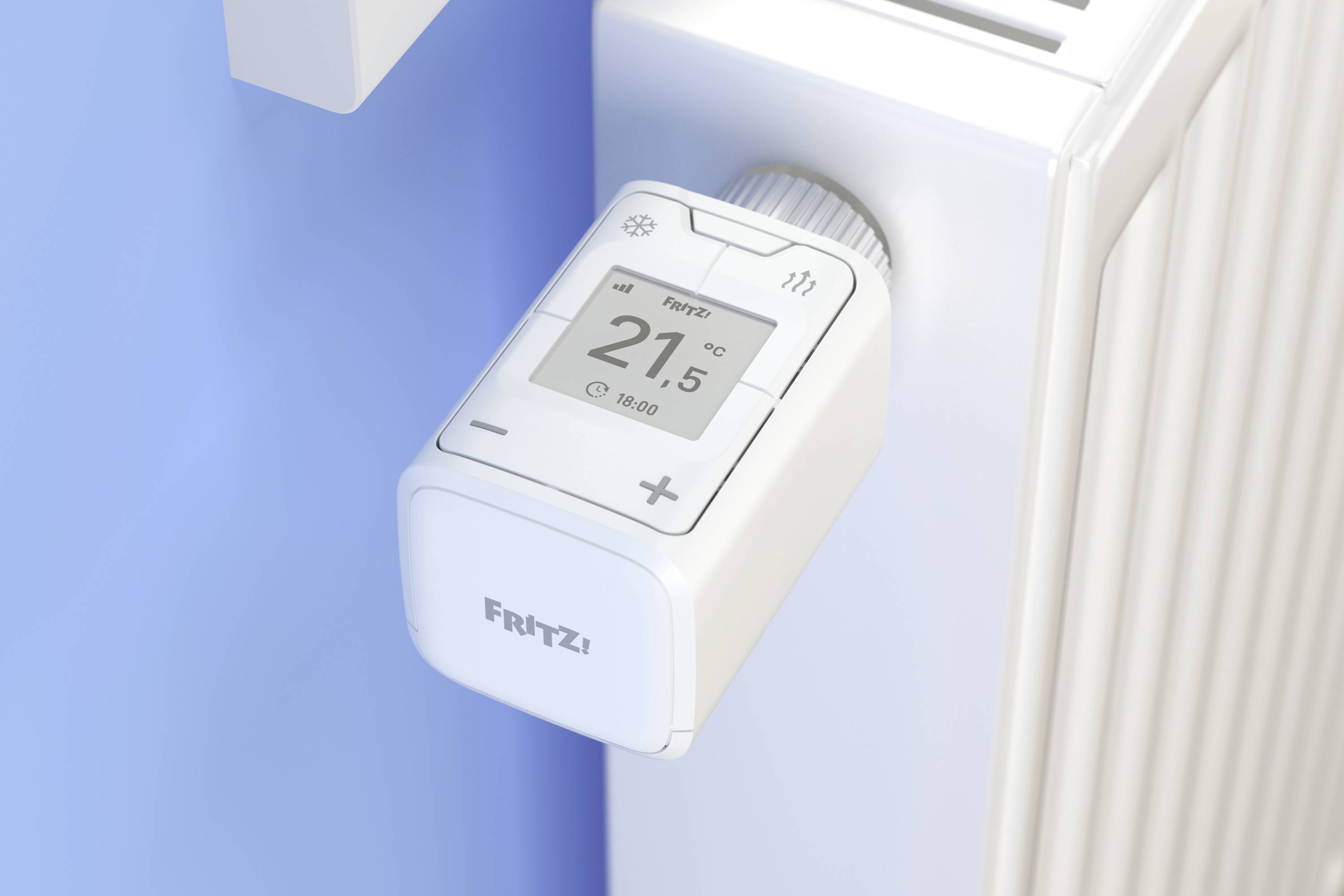 Ein digitales Heizkörperthermostat zeigt '21,5°C' an. Es ist an einem weißen Heizkörper angebracht und wird per Knopf bedient.