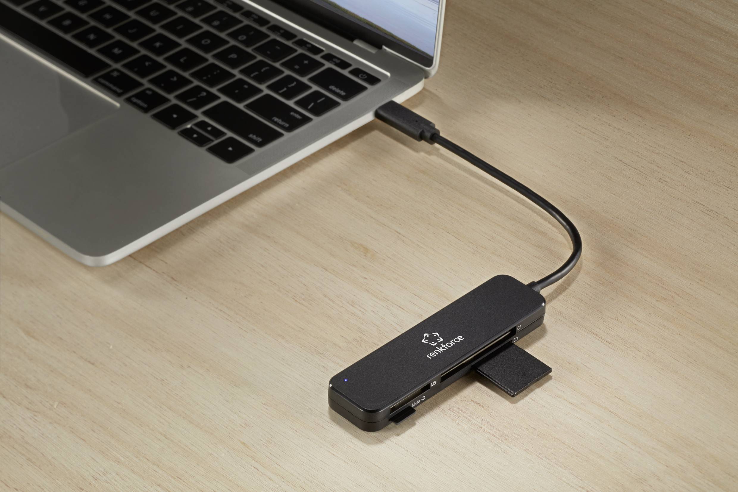 Ein Laptop ist mit einem schwarzen USB-Hub verbunden, der mehrere Anschlüsse bietet, darunter USB- und Speicherkartensteckplätze.