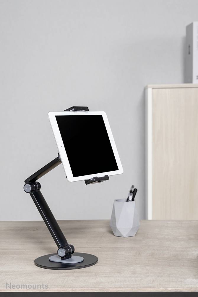 Tablet auf verstellbarem Armständer auf Schreibtisch; im Hintergrund ein Stifthalter und ein Aktenschrank.