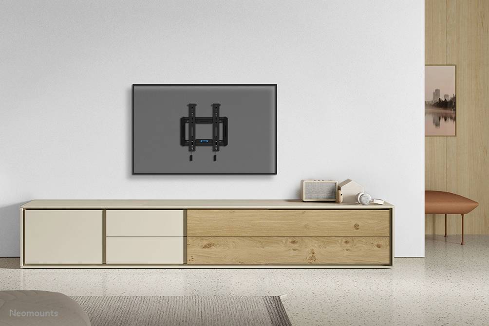 Ein moderner Wohnraum mit einem niedrigen Holz-Sideboard. An der Wand hängt ein großer, dunkler Fernseher.