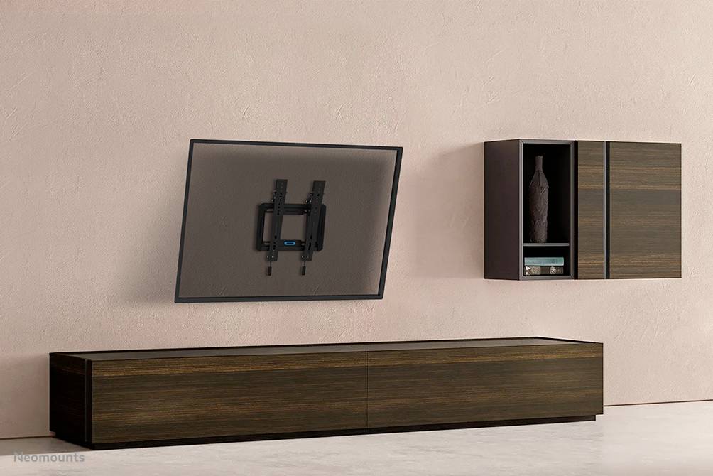 Ein schwenkbarer Fernseher ist an einer Wand mit einem Holzschrank montiert. Neben dem Fernseher befindet sich ein Regal mit Dekorobjekt.