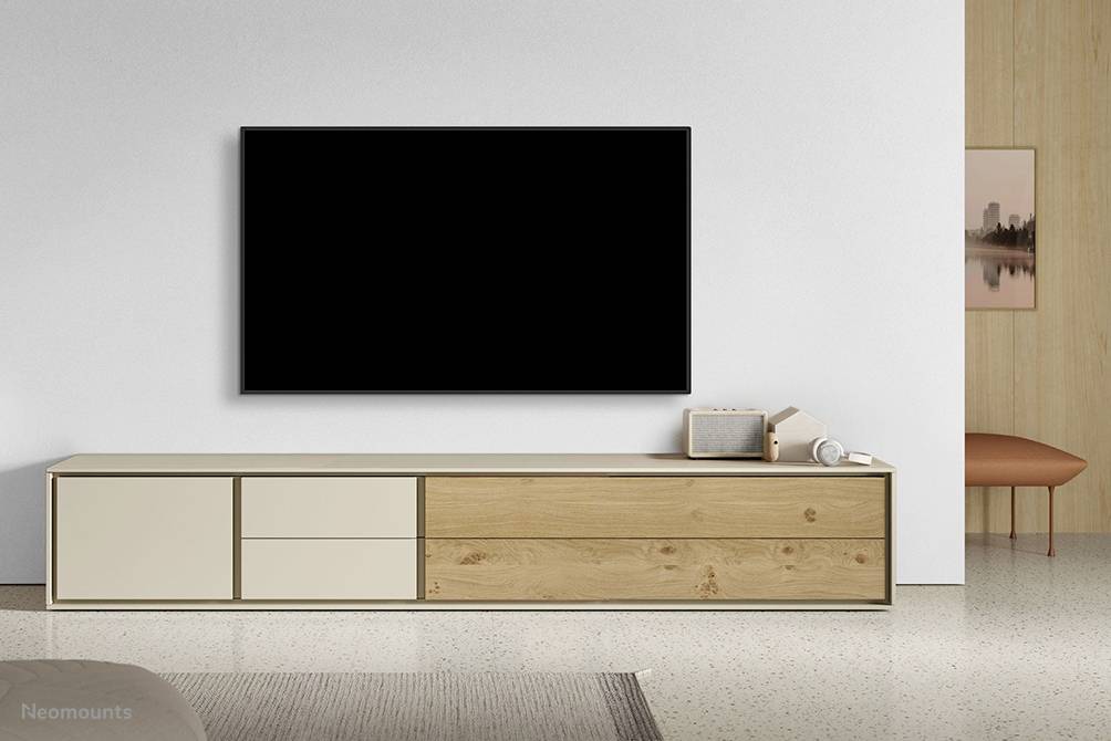 Ein flacher Fernseher an einer weißen Wand, darunter ein minimalistisches Holz- und Hellbeige-Sideboard mit drei Schubladen und zwei Türen.