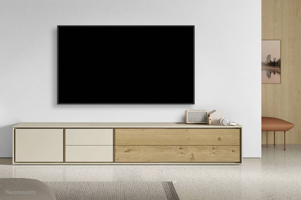Ein modernes Wohnzimmer mit einem großen, schwarzen Fernseher an der Wand. Darunter steht ein minimalistisch gestaltetes Sideboard.