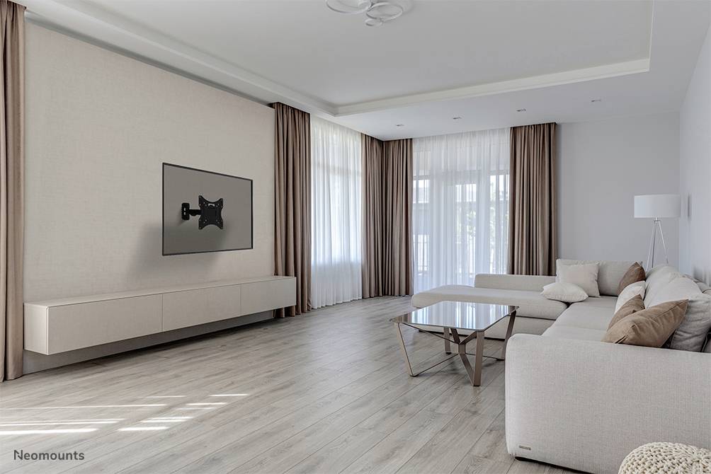 Minimalistisches Wohnzimmer mit cremefarbenem Sofa, Glas-Couchtisch, wandmontiertem Fernseherhalter und großen Fenstern mit Vorhängen.