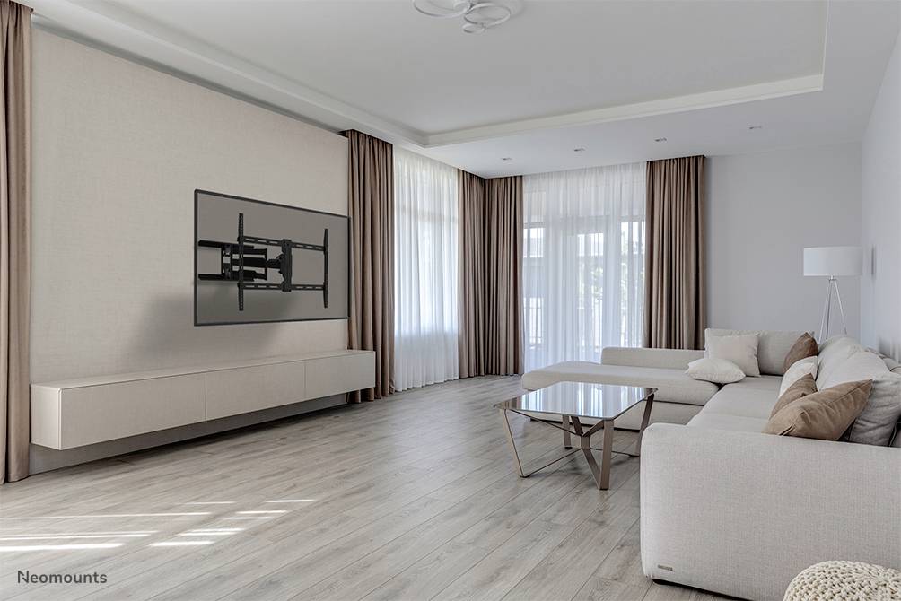 Modernes Wohnzimmer mit großer beige Couch, Glas-Couchtisch und wandmontiertem TV-Halter. Große Fenster mit Vorhängen flankieren den Raum.