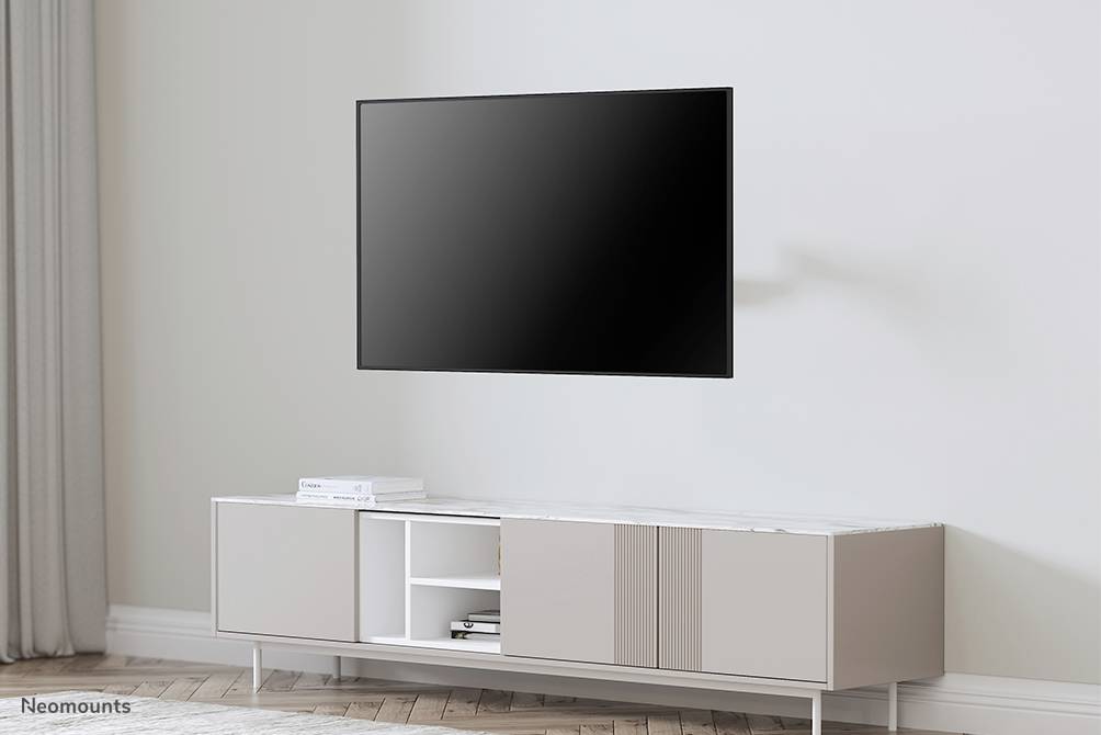 Ein moderner Flachbildfernseher hängt an einer Wand über einem minimalistischen, weißen TV-Schrank in einem hellen Raum.