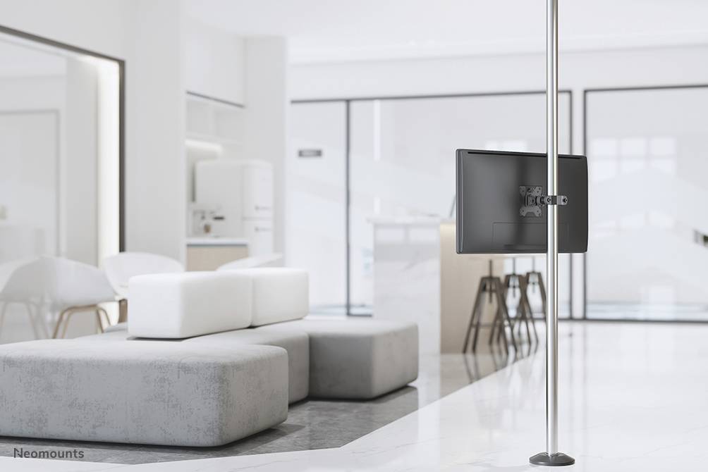 Ein moderner, heller Raum mit weißen Möbeln und einem grauen Sofa. Rechts im Bild steht ein Flachbildschirm auf einem hohen Ständer.