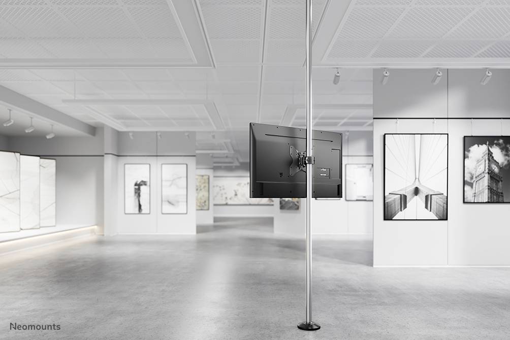 Ein moderner Kunstgalerie-Raum mit mehreren an den Wänden hängenden Kunstwerken. Im Vordergrund steht ein freistehender Bildschirm.