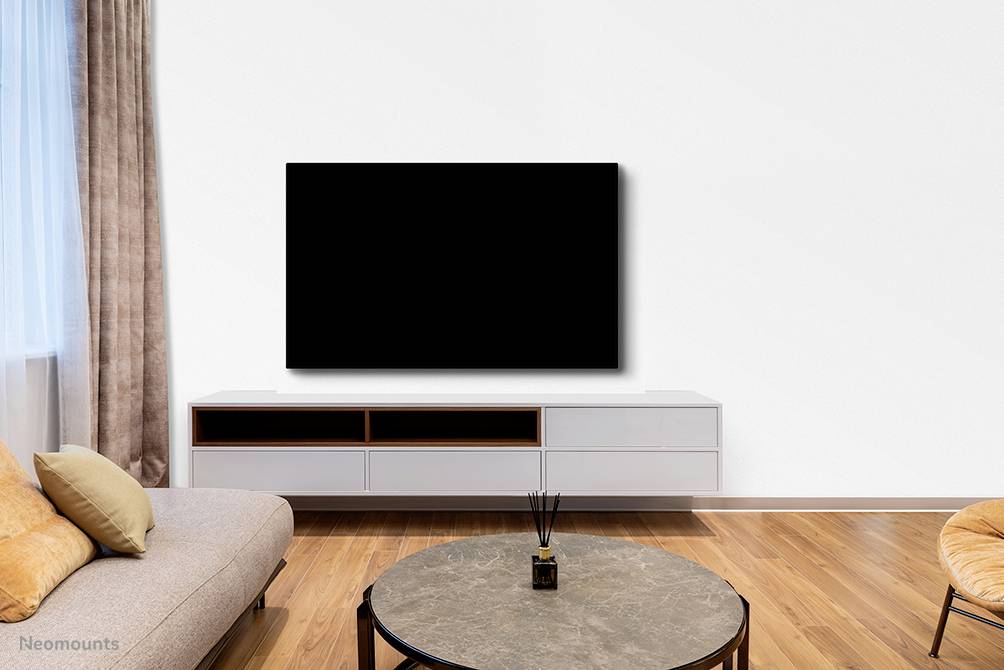 Ein modernes Wohnzimmer mit Holzboden, Sofa, Couchtisch und großem, schwarzen Fernseher an der weißen Wand montiert.