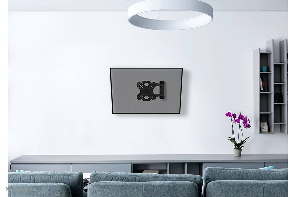 Wohnzimmer mit grauem Sofa, Wandregal, Orchidee auf Kommode und wandmontierter TV-Halterung ohne Fernseher an weißer Wand.